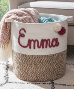 De TERRA - stevige opbergmand van jute en katoen is gevuld met gevouwen roze en blauwe dekens en ligt op een gedessineerd kleed naast een beige bank.