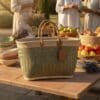 De MADA - ruime en handgemaakte shopper in natuurlijke vezels staat op een picknicktafel vol fruit, brood, tomaten en lavendel, met drie mensen op de achtergrond in de buitenlucht.
